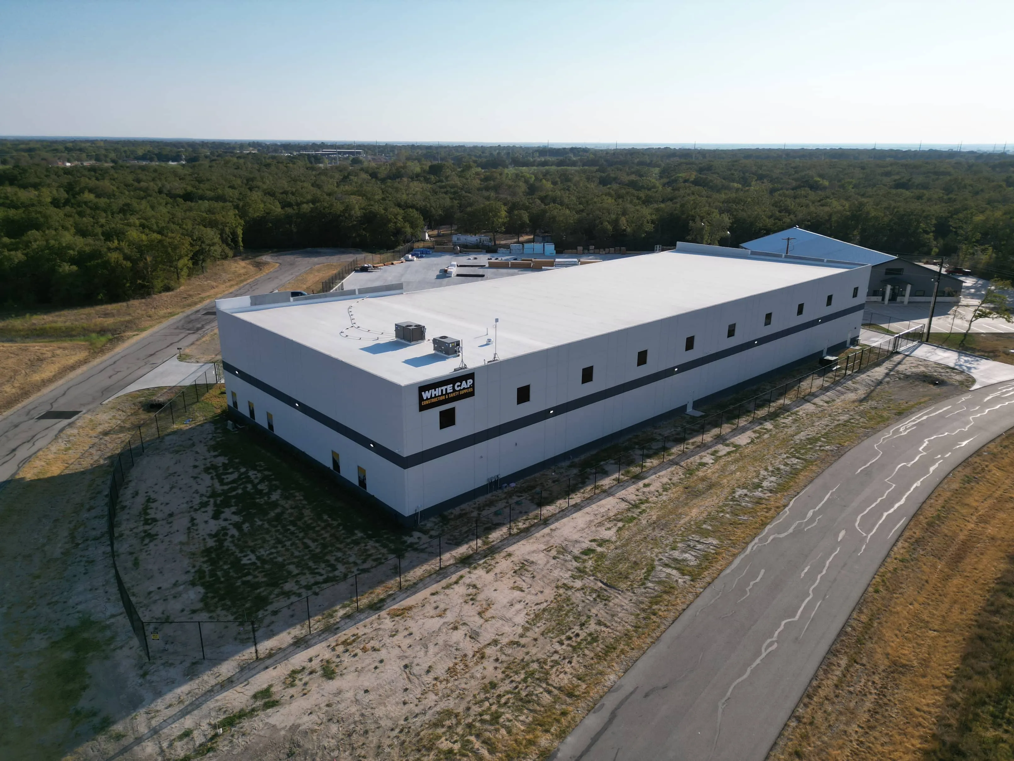 Aerial view of a white building beside a curved road at White Cap College Station